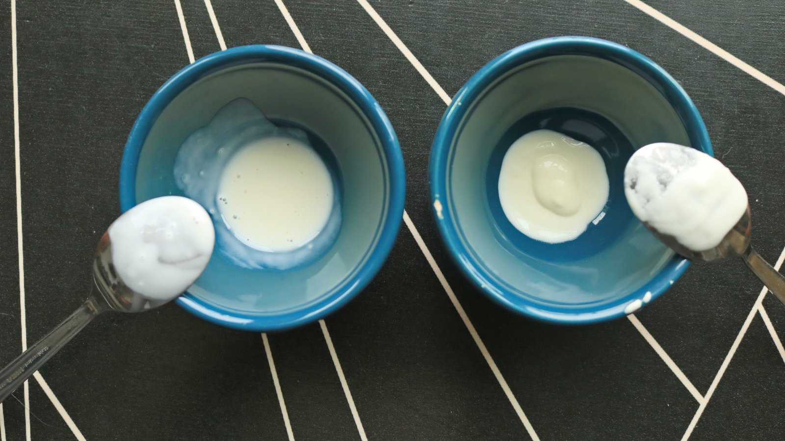 Two small bowls and spoons with two different creams inside.